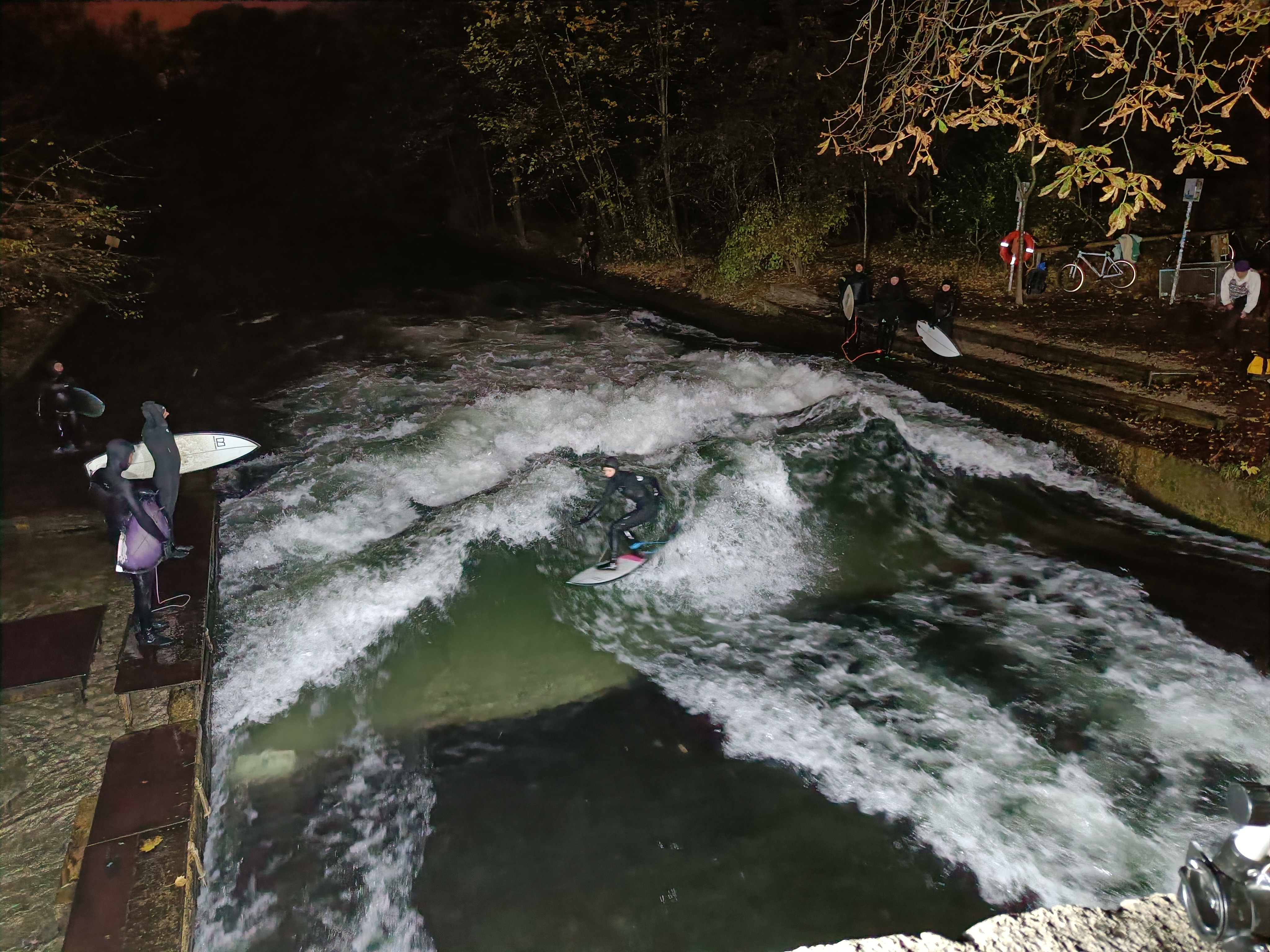 Surfers braving the chilly waters in Munich at 9 PM