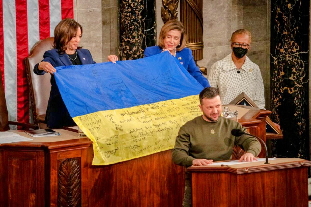 Ukrainian President Zelensky presents a battle flag to US Congress representatives in December 2022