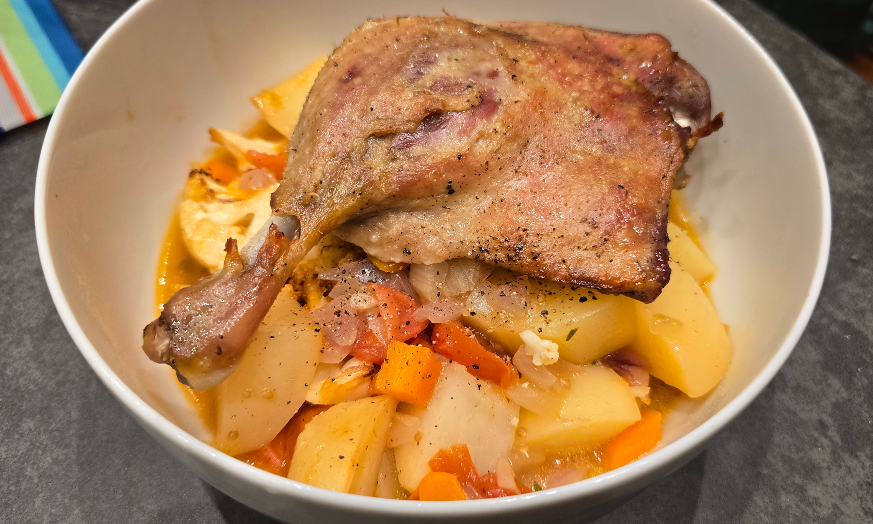 Indulging in a gourmet confit duck leg served with a delightful mixed vegetable cassoulet