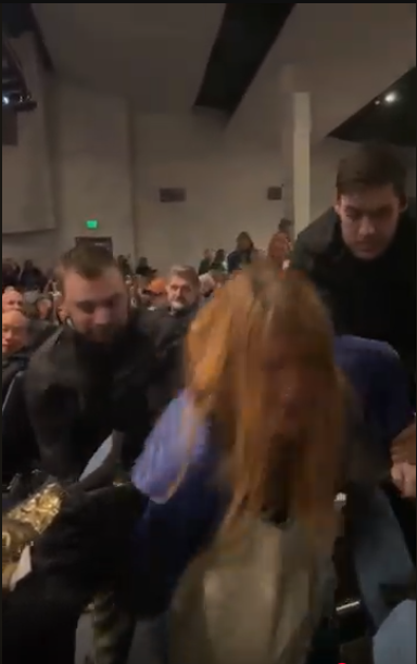 Unidentified Men in Black Jackets Forcefully Remove Woman from Public Meeting