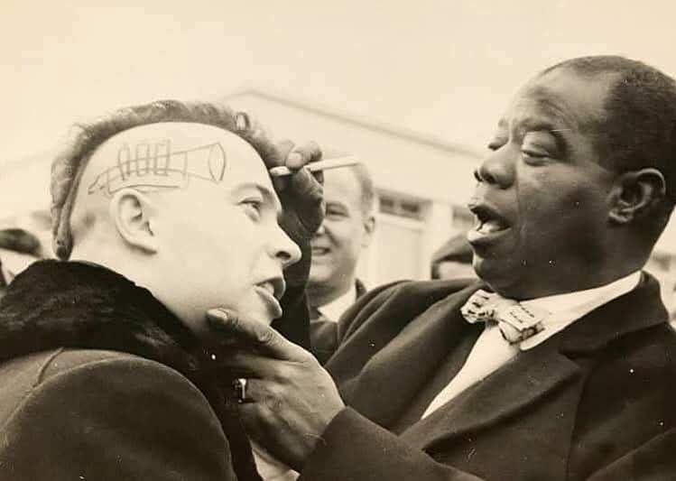 Louis Armstrong signing a punk's forehead in France, 1961