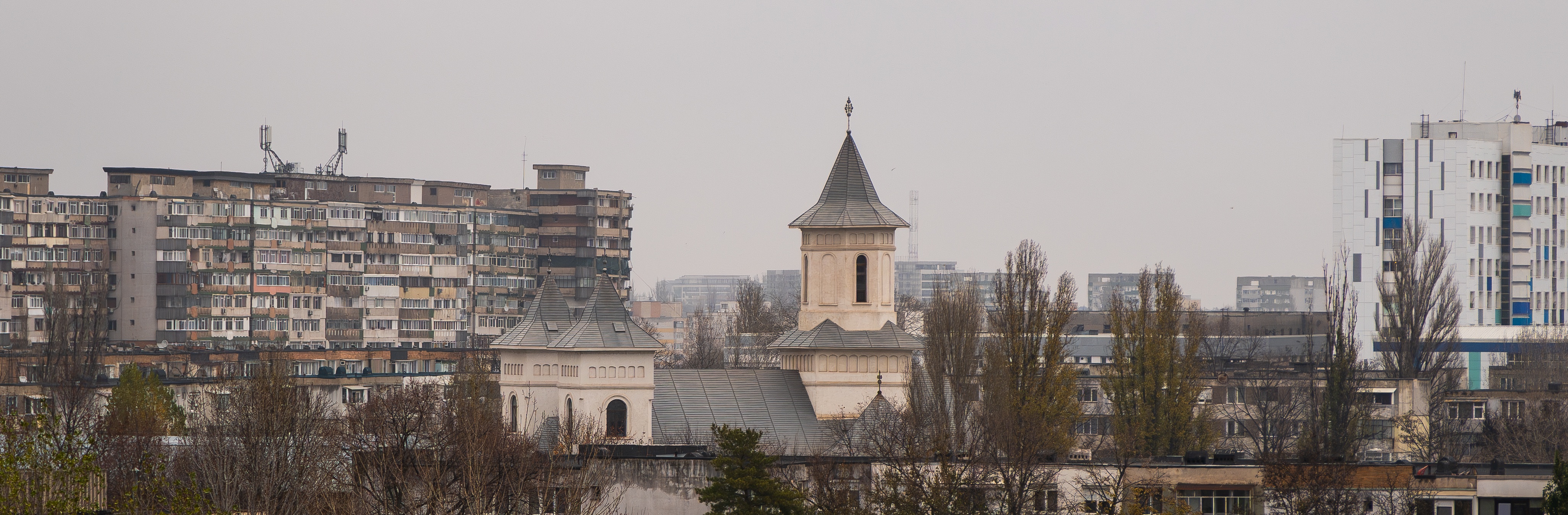 A vibrant new church shines amidst the rain-soaked Soviet-era skyline.