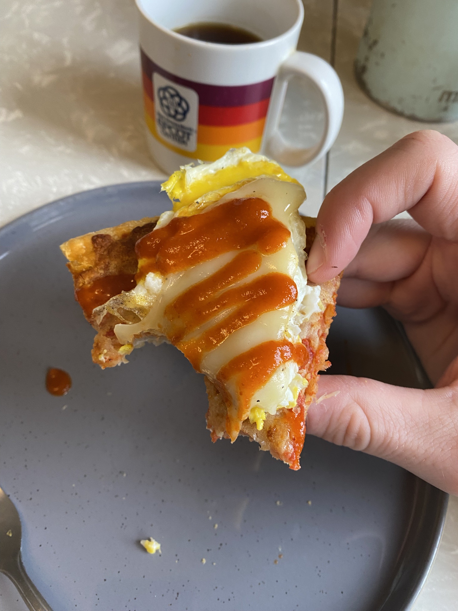 Indulging in Cold Pizza Topped with Hot Egg and Sriracha