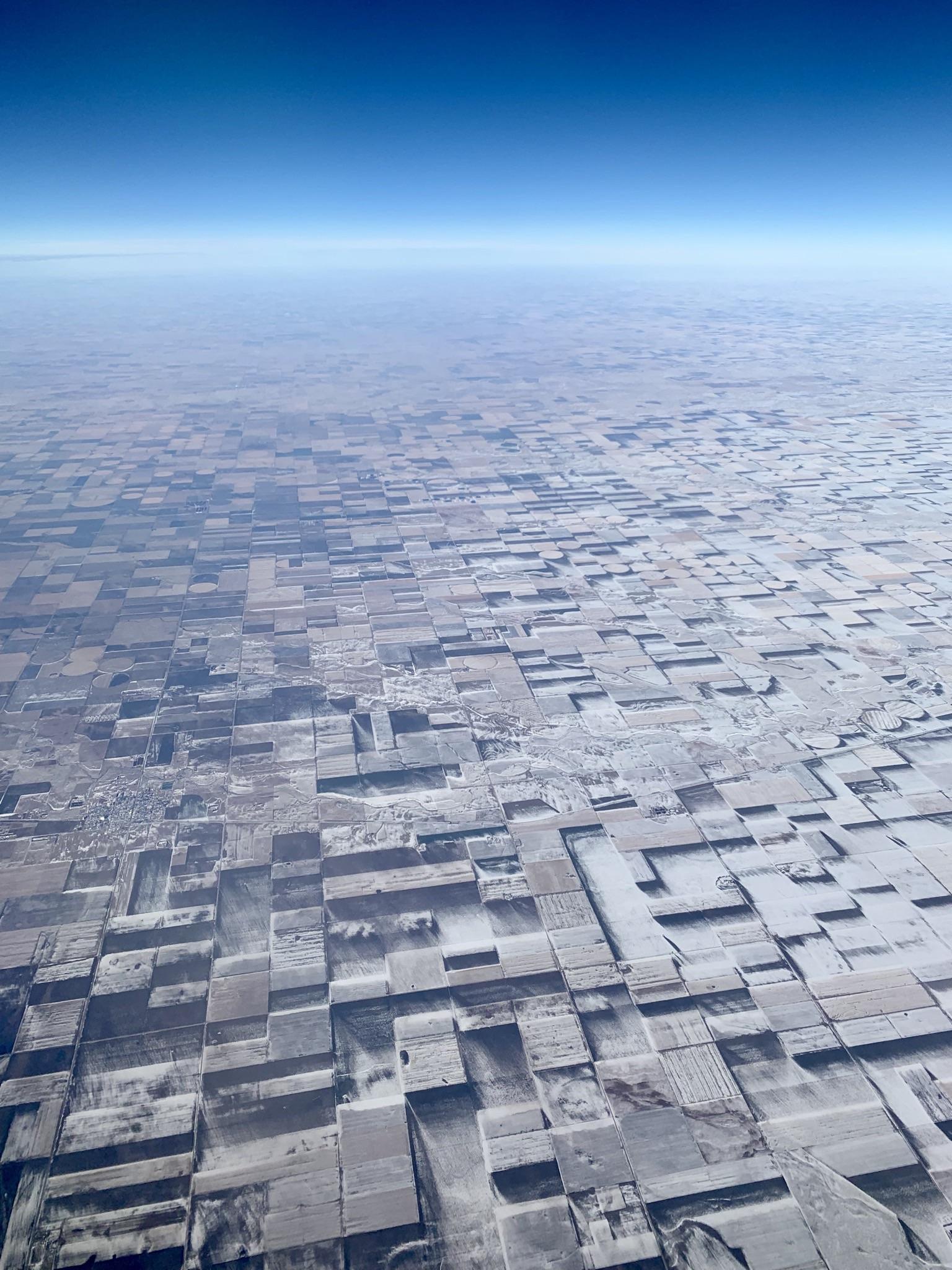 Aerial view of endless flat farmland in eastern Colorado, where snow drifts create a mesmerizing cubist illusion.