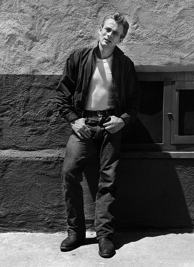 James Dean exuding effortless cool while leaning against a wall.