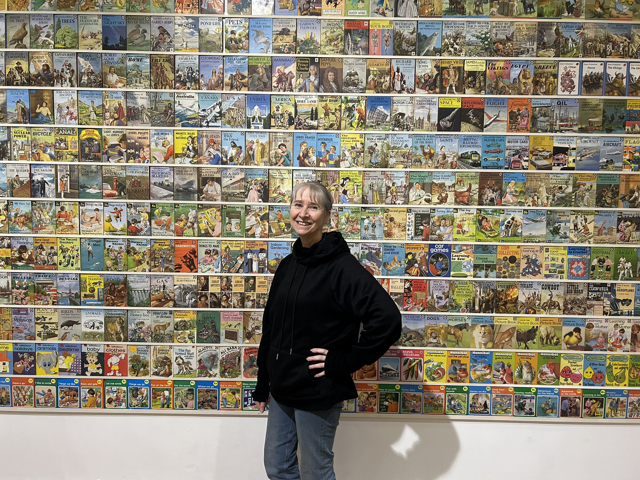 Helen Day Surrounded by a Wall of Ladybird Comics at Peterborough Museum