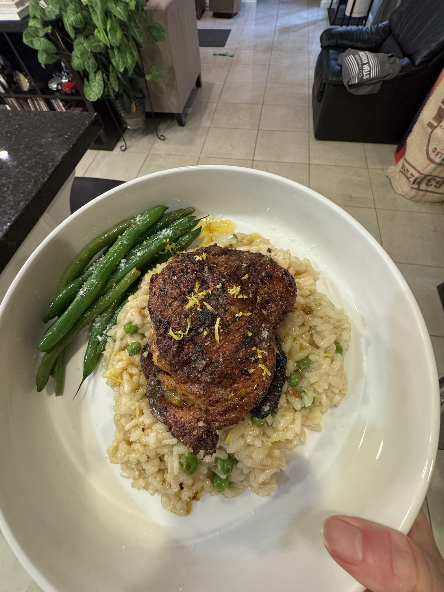 Savoring a delicious roasted chicken thigh served with creamy mushroom and peas risotto alongside garlic green beans