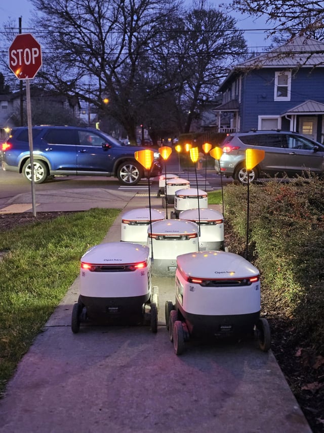 Food Delivery Robots Patiently Waiting to Cross the Road