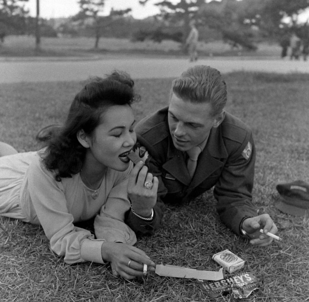 A touching moment: A US soldier shares chocolate and cigarettes with a girl in Japan, 1946.