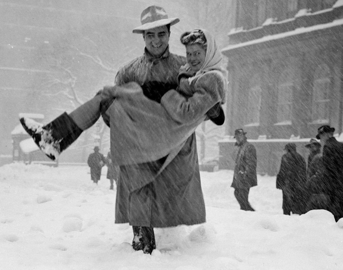 A fortunate lady shares a ride with a true gentleman on a snowy day in 1947.