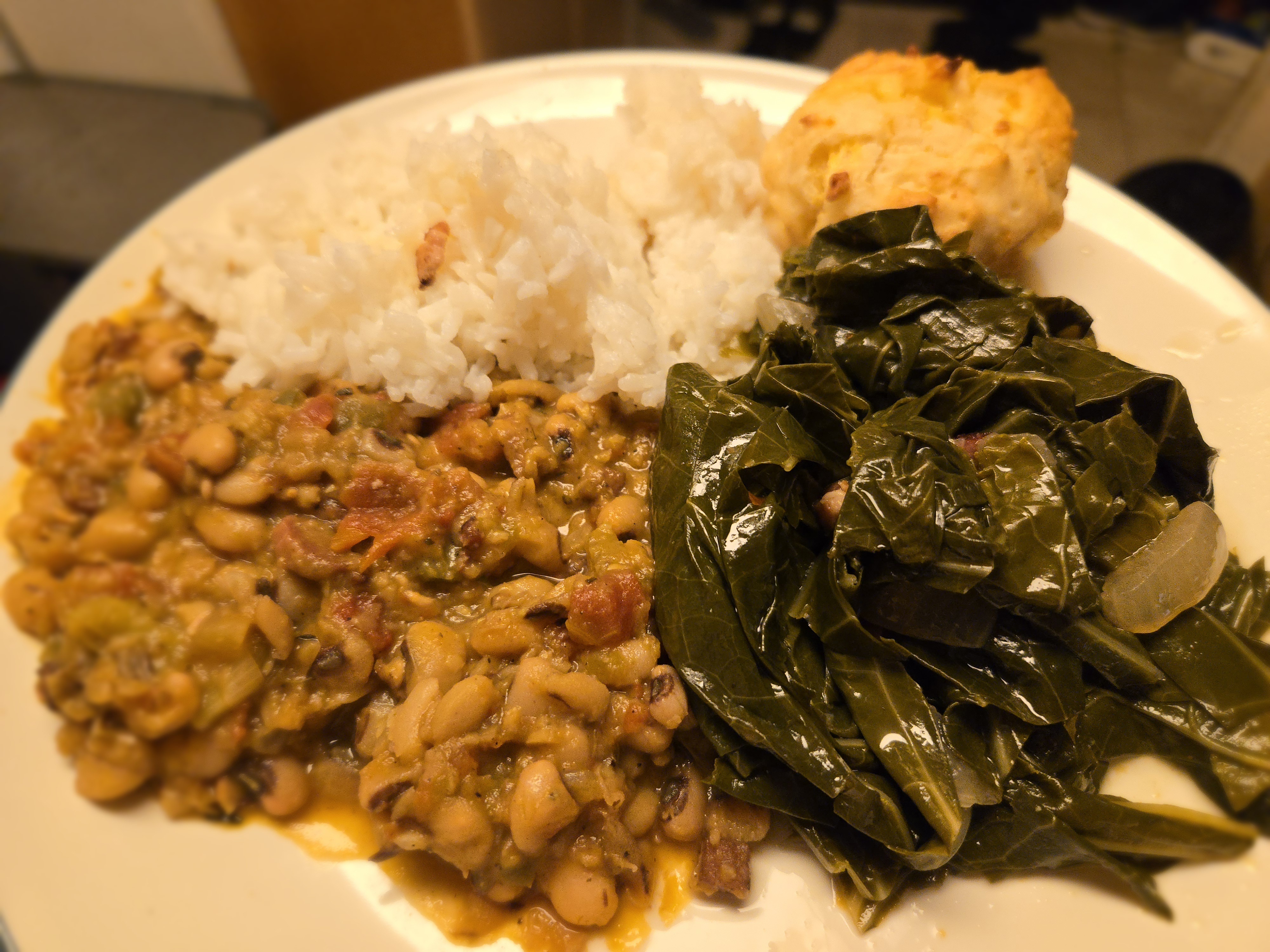 Delicious Hoppin' John served with collard greens, rice, and a fluffy biscuit.